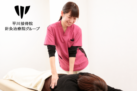 うつ伏せの利用者に腰の施術を行うスタッフ