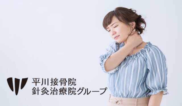 首に手を当てて痛みを感じる女性