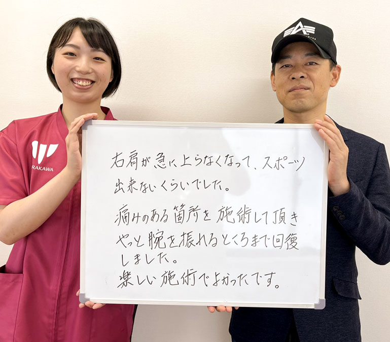右肩の回復について書かれた感想ボードを持つ利用者とスタッフ